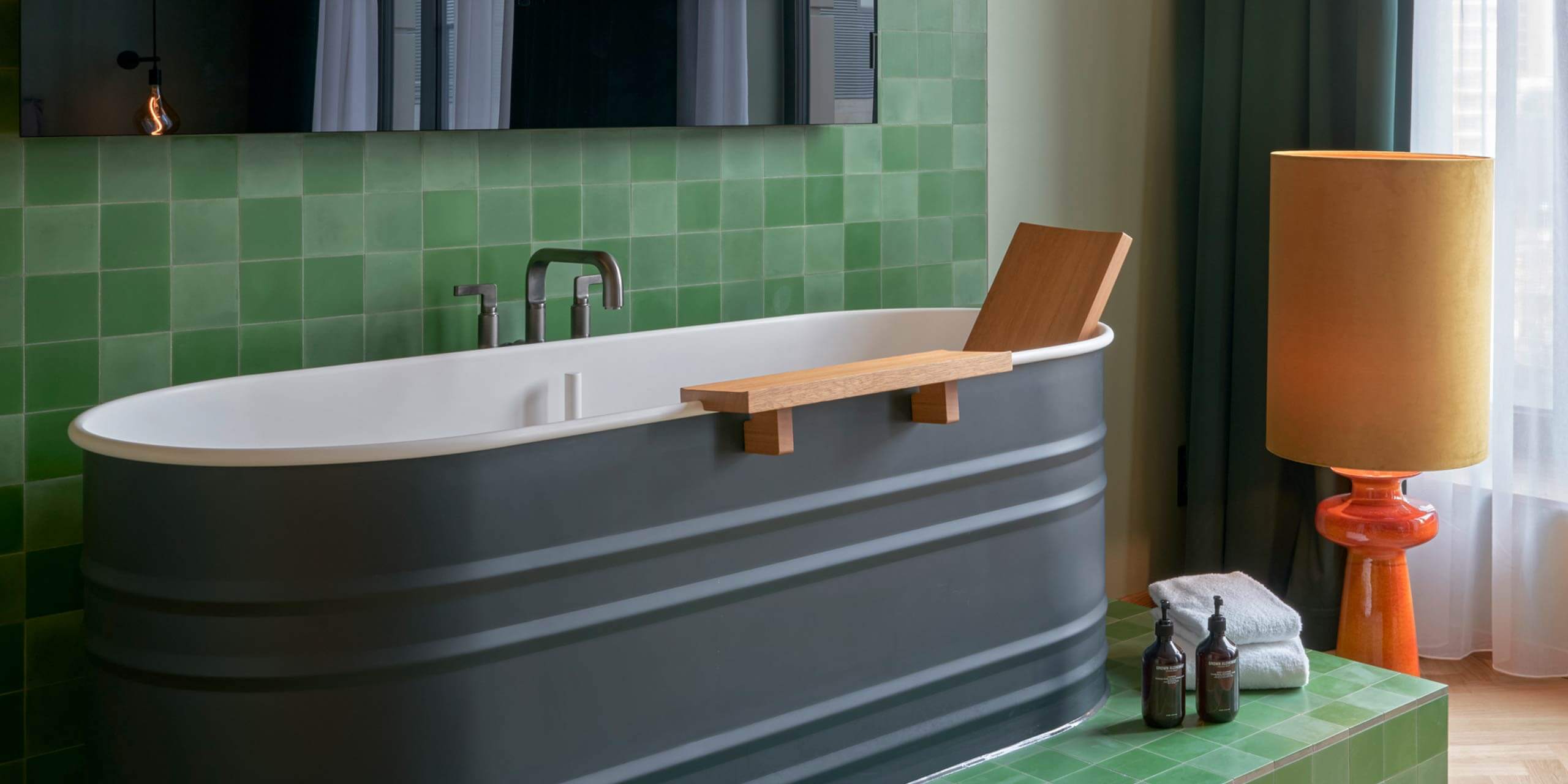 Junior Suite: grün gekachelter Badewannenbereich im Raum unter dem Fernseher